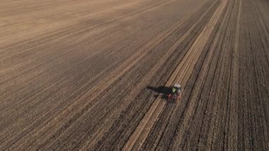 Modern tractor working on farmland, cultivating soil after harvest. Tractor plowing agricultural field. Concept of agriculture, harvest and farming machinery