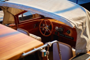 Close up of wooden steering wheel and dashboard inside motorboat cabin. Concept of boating, water transport and luxury travel