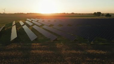 Güneş panelleri ve kırsal alanda güneş batarken rüzgar türbinleri. Yenilenebilir enerji kavramı, sürdürülebilir teknoloji ve temiz elektrik üretimi