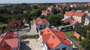 Aerial view of residential neighborhood with modern houses, construction site, streets and green trees in small town
