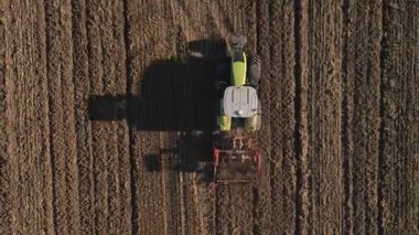 Modern tractor working on farmland, cultivating soil after harvest. Tractor plowing agricultural field. Concept of agriculture, harvest and farming machinery