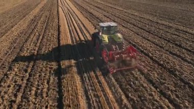 Modern tractor working on farmland, cultivating soil after harvest. Tractor plowing agricultural field. Concept of agriculture, harvest and farming machinery