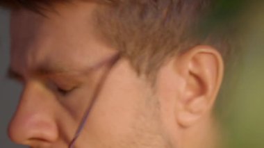 Close up of fatigued man removing glasses and rubs his eyes showing tiredness and stress. Male freelancer working late at home office. Concept of overwork, burnout, eye strain and exhaustion at work