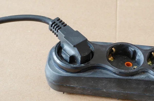 在米色背景上使用电源线 插有插头的黑色开发人员 电气安全规则 有选择的重点 — 图库照片