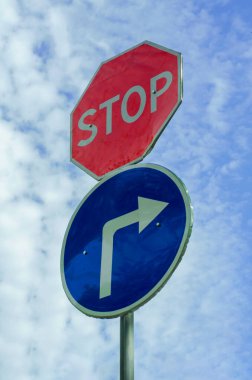 Yol işareti dur ve bulutlu gökyüzünün arka planında hareket var. Bir sütunda iki yol işareti. Belirsiz motivasyon arkaplanı.