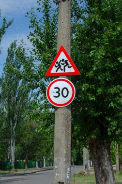 Yol hız limiti 30 ve yeşil bir caddede çocukları uyarın. Bir sütunda iki yol işareti. Yol güvenliği, okul..