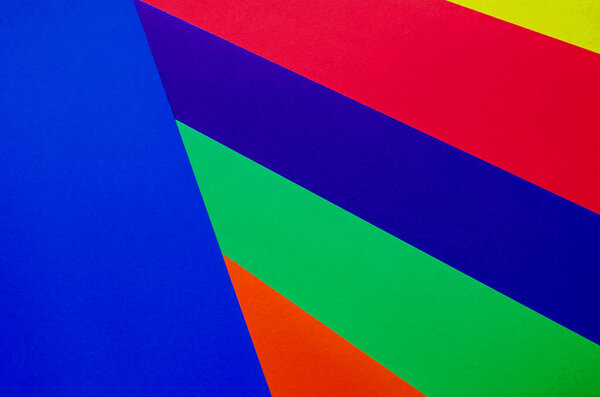 Multicolored paper background. Paper sheets of rainbow colors close-up. Geometric multitask background. Place for text. View from above.