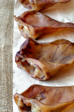 Çuval bezinde dört kurutulmuş domuz kulağı. Evcil hayvan plağındaki diş temizliği için diş tedavisi. Hayvan malzemeleri..