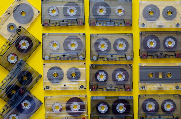 Vintage audio cassettes on a yellow background. 90s music on audio cassettes. Many audio tapes with old songs. Copy space