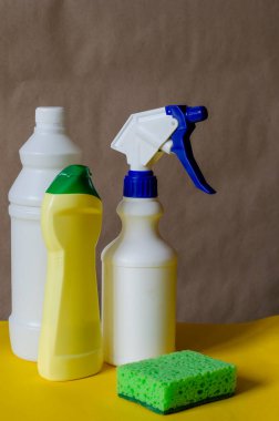 İki renkli arka planda temizlik ürünleri ve süngerli plastik şişeler. Evdeki kimyasallar için çeşitli konteynırlar. Temizlik şirketleri ya da ürünler. Yan görüş. Yakın plan..