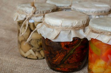 Konserve mantar, lecho ve diğer ev yapımı konserveler. Cam kavanozlarda konserve yiyecekler. Çuval bezinde çeşitli konserveler. Ekinlerin korunması ve depolanması. Yakın plan..