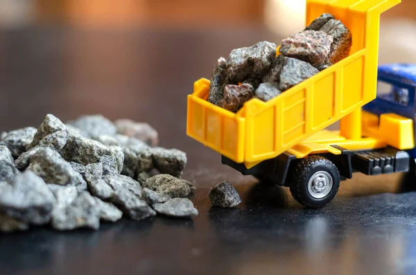 Çocuk kamyonu için plastik oyuncak. Sarı damperli kamyon cesetten çakıl döküyor. Çocuklar için oyuncaklar. Eğitici oyunlar. Seçici odaklanma. Yakın plan..