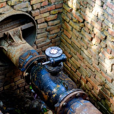 Tuğla kuyusunda valfleri olan açık bir yeraltı boru hattı. Su ve ısıtma kaynaklarının yeraltı iletişimi. Onarım ve yenileme işlemi.