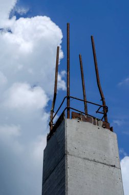 Gökyüzüne karşı takviyeli beton yığını. Monolitik güçlendirilmiş sütunların temeli üzerine modern bir bina inşa etmek. Aşağıdan yukarıya bak. Sanayi geçmişi.