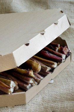 Evcil hayvanlar için doğal kurutulmuş ikramlar. Köpekler için boğa sopaları. Biftekli karton kutu. Hayvan ürünleri.