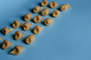 Açık mavi arka planda insalonde makarna ile yaratıcı bir arka plan. Geleneksel Akdeniz Mutfağı Malzemeleri 'nden geometrik şekiller ve çizgiler. Gastronomi. Boşluğu kopyala.