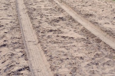 Kumda arabanın izleri var. Kumlu bir yoldaki bir cipin lastik izleri. Seyahat, turizm ve tatil. Seçici odak.