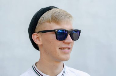 Sarışın, neşeli ve iyimser bir gencin portresi ilgiyle uzaklığa bakıyor. Mavi güneş gözlüklü, siyah şapkalı, gülümseyen bir maceraperest. Yaş 20-22. C