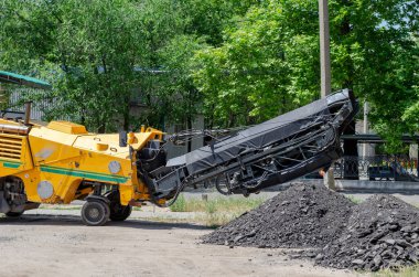 Sarı Asfalt Yolu Değirmen Kesicisi. Eski ezilmiş asfalt yığınının yanında yol yapımı makineler. Özel ekipman.