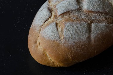 Küçük bir iş. Aile Fırını Konsepti. Siyah arka planda bir somun ekmek. Fırıncı mı? Seçici odak.