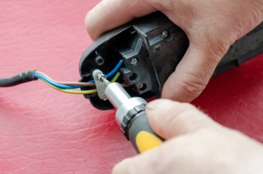 Elektrikçi tornavidayla elektrik dağıtıcısını monte ediyor. Elektrik kablosu tamiri. Elektrik emniyeti. Bir açıdan üstten bak. Seçici odak.