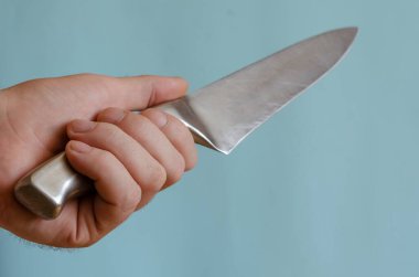 Yetişkin bir adam elinde metal saplı bir mutfak bıçağı tutuyor. Paslanmaz çelik bıçak 20 cm uzunluğunda. Avrupalı erkek, 43-45 yaşlarında. Mutfak aletleri