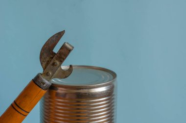 Closed can and can opener. Canned food and a special knife. Long-term storage products. Close-up. Copy space. clipart