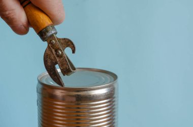 Adamın elleri, tahta saplı eski bir konserve açacağıyla teneke kutuyu açıyor. Konserve yemek ve özel bir bıçak. Avrupa ırkından yetişkin bir erkek.