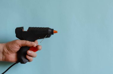 Erkek elinde tutkal termometresi. Nesneleri yapıştırıcı çubuklarıyla yapıştırmak için elektrikli bir cihaz. Avrupa ırkının orta yaşlı adamı. Çalışma ve yaratıcılık için elde taşınabilir elektrikli araçlar