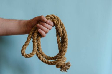 Erkek eli düğümlü kenevir ipi tomarı. El kalın bir doğal kabloyu tutar. Avrupa ırkından yetişkin bir erkek. Denizciler. Spor ve eğlence..