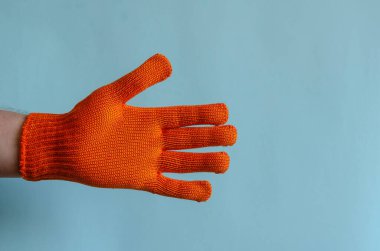 Mavi arka planda kırmızı iş eldiveni. Koruyucu eldivenli bir adamın eli, açık bir avuç içinin göstergesidir. Erkek Avrupa ırkı. İş güvenliği, iş kıyafeti.