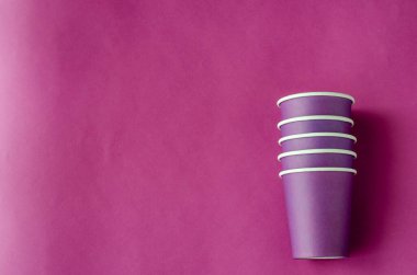 Kahve için bir yığın leylak kağıt bardak. Mor arka planda tek kullanımlık gözlükler. Çevre dostu yemekler. Uzayı kopyala Seçici odak.