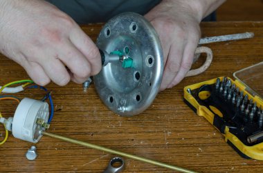 Su ısıtıcısının 27. bölümünün tamiri. Bir adamın elleri kazan dairesine ısıtma elementi yerleştirebilir. Ev aletlerinin bakım ve onarımı.