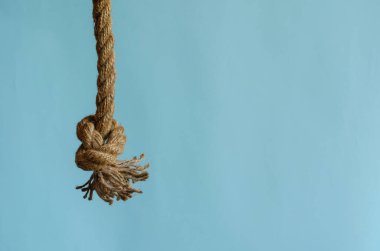 Açık mavi arka planda düğümlü kenevir otu ipi. Denizciler. Spor ve eğlence sektörü. Yakın plan. Boşluğu kopyala.