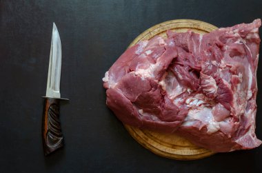 Kesme tahtası ve bıçağında büyük bir parça taze domuz filetosu. Çiğ domuz budu. Et ticareti, kasap dükkanı. Yukarıdan görüntüle.
