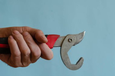 Erkek elinde evrensel anahtar. Bir adamın eli siyah ve kırmızı saplı bir alet gösteriyor. Avrupa ırkının orta yaşlı adamı. El aracı.