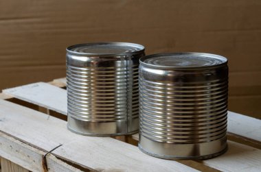Kutularda konserve yiyecekler. İki metal kapaklı hazır yemek kavanozu. Uzun vadeli gıda ürünleri. Bir açıdan üstten bak. Seçici odak.
