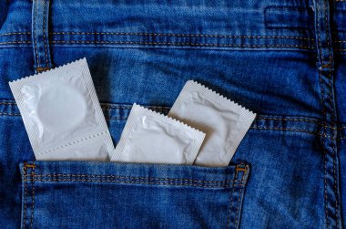 Kot pantolonun arka cebinde birkaç prezervatif var. Ergenlik çağında cinsel eğitim. Doğum kontrol hapı. Yukarıdan görüntüle.