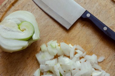 Kesme tahtasında çiğ soğan. Yakınlarda doğranmış soğan kepçesi. Yemek hazırlama süreci. Doğanın şakaları. Yukarıdan görüntüle.