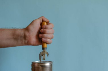 Adamın elleri, tahta saplı eski bir konserve açacağıyla teneke kutuyu açıyor. Konserve yemek ve özel bir bıçak. Avrupa ırkından yetişkin bir erkek.