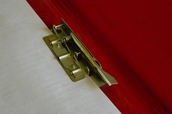 Red paper folder with clip close-up. Open folder with a metal clip. Office work, stationery. Copy space. Selective focus.