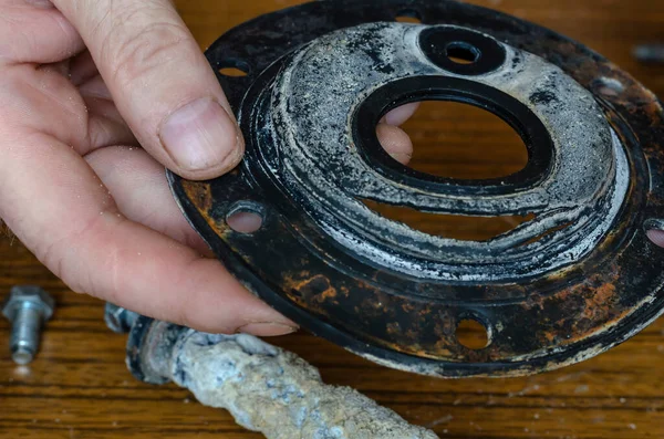 Close-up of a man\'s hands showing a torn rubber gasket for a water heater. Repair and maintenance services for home appliances. Eye level shooting. Selective focus.