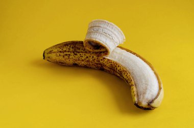 Sarı arka planda kahverengi benekli, olgunlaşmış bir muz. Muzlu ekmek, tatlı ve diğer yemekler için malzemeler. Sağlıklı beslenme. Seçici odak.