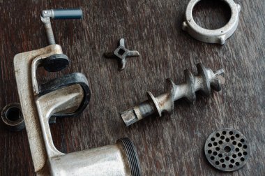 Tahta masada parçalanmış eski model kıyma makinesi. Kıyma makinesi, çalı çırpı, ızgara, özel bıçak ve fındık döküm demir gövde. Yukarıdan bir açıyla ateş ediyorlar. Eski mutfak gereçleri.