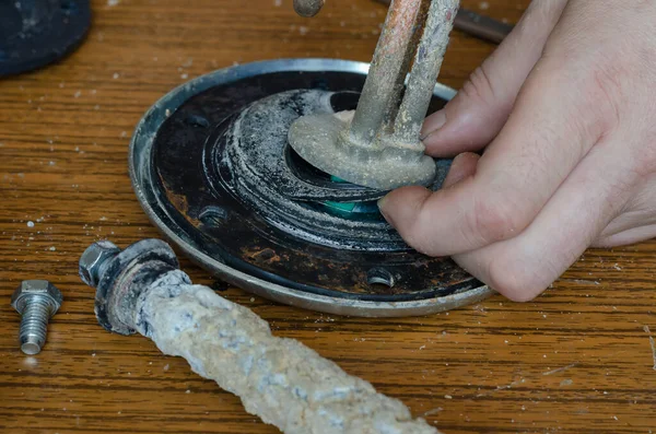Bir adamın ellerinin, su ısıtıcısı için lastik conta yırtıldığını gösteren yakın plan fotoğrafı. Ev aletleri için onarım ve bakım hizmetleri. Göz hizasında atış. Seçici odak.