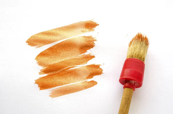 Round brush and smear of orange paint. Watercolor paint and round brush on a white background. Abstract background. Selective focus.