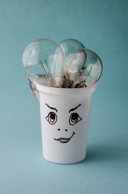 Yaratıcı arka plan mantıklı iş düşüncesi. Yeni fikirler, modernleşme arayışı. Yanmış ampullerle dolu beyaz plastik cam. Bir cama şematik olarak çizilmiş yüz..