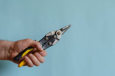 Erkek eliyle metal kesme makası. Adamın eli siyah ve sarı saplı bir aleti tutuyor. Avrupa ırkının orta yaşlı adamı. El kesme aracı.