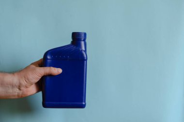 Bir adamın elinde tam mavi bir kutu. Bir adamın eli plastik bir teneke kutuyu sıvı halde tutuyor. Avrupa ırkının orta yaşlı adamı. Araba servisi, otomobil ürünleri..