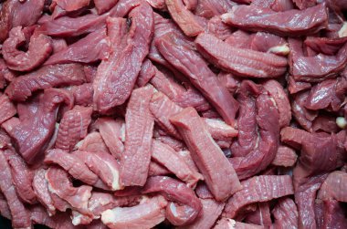 Rastgele hazırlanmış sığır eti şeritleri arka planı. Biftek fileto küp küp doğranmış. Çiğ et dokusu. Seçici odak.